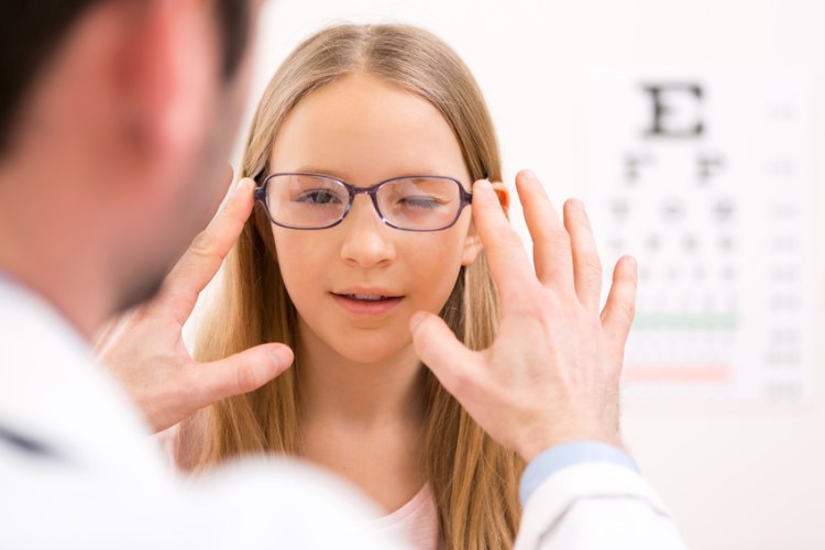 Young little girl trying glasses at the optician
