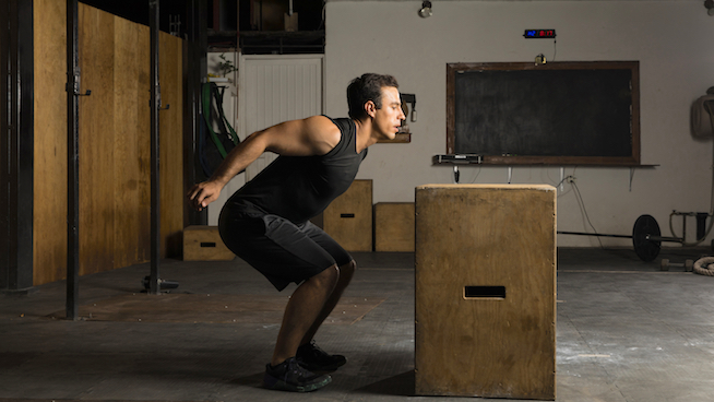 Young man jumping a box at the gym